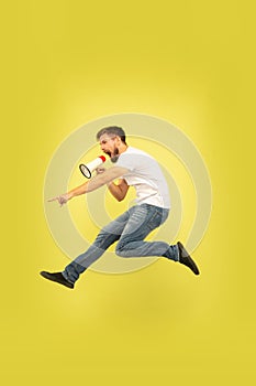 Full length portrait of happy jumping man on yellow background