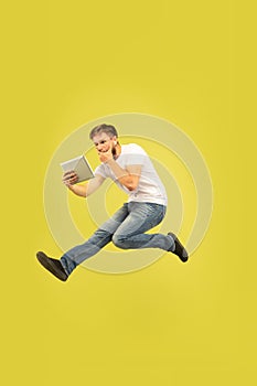 Full length portrait of happy jumping man on yellow background