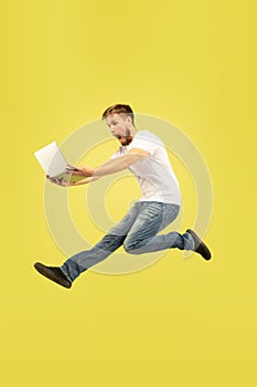 Full length portrait of happy jumping man on yellow background