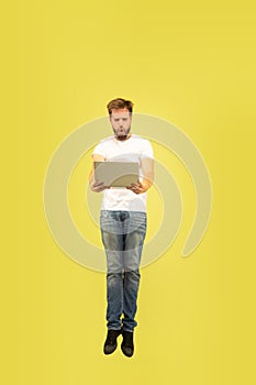 Full length portrait of happy jumping man on yellow background