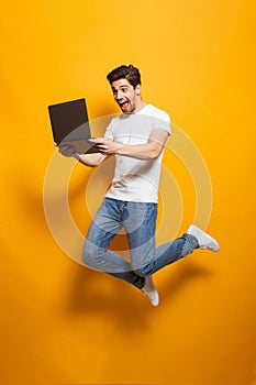 Full length portrait of happy man with brown hair jumping and ho