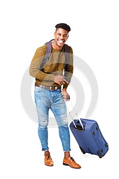 Full length happy young black man standing against isolated white background with travel bags and cellphone