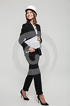 Full length portrait of a happy young woman in hard hat