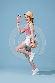 Full length portrait happy young woman holding traveling tickets with passport and jumping isolated over blue background