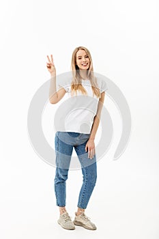 Full length portrait of a happy young woman standing and showing peace gesture with two hands isolated over white