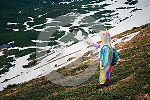 Female hiker in unicorn costume talking selfie in mountains