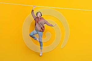 Full length portrait of impressed person hand hold hang rope empty space  on yellow color background