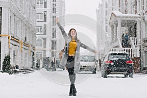 Full-length portrait of inspired female model in stylish coat posing with pleasure in winter city. Outdoor photo of glad