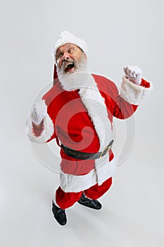 Full-length portrait of joyful senior man wearing Santa Claus costume isolated over white background. Holiday season