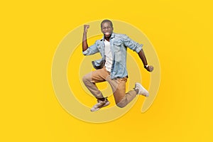 Full length portrait of joyous ecstatic man jumping for joy or flying. indoor studio shot  on yellow background