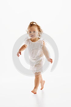 Full-length portrait of little girl with wet curly hair have fun while running against white studio background. Fun and