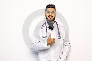 Full length portrait of a male doctor standing and giving a thumb up on white background
