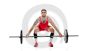 Full length portrait of man in red sportswear exercising with a weight isolated on white background. Sport