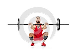 Full length portrait of man in red sportswear exercising with a weight isolated on white background. Sport