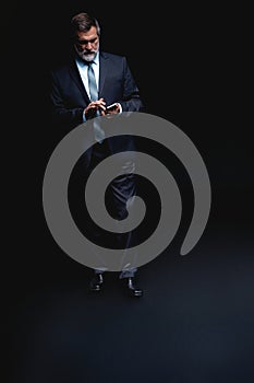 Full length portrait of Mature business man wearing formal suit standing on black background.