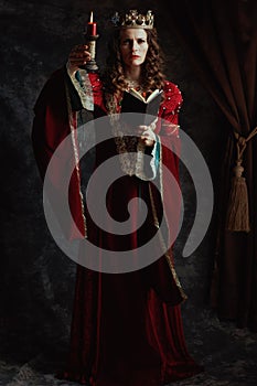 Full length portrait of medieval queen in red dress with book