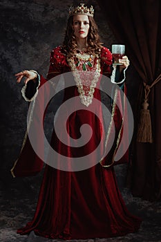 Full length portrait of medieval queen in red dress with goblet