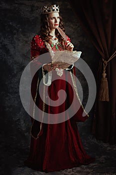 Full length portrait of pensive medieval queen in red dress