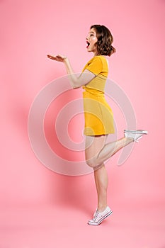 Full length portrait of playful attractive woman in yellow dress
