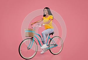 Full length portrait of pretty black woman in casual clothes riding vintage bicycle on pink studio background