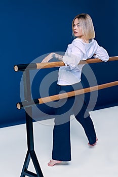 Full length portrait of a pretty blonde woman standing back side to the camera with hands lay on wood stick