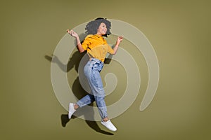 Full length portrait of pretty lady jumping empty space wear yellow shirt isolated on khaki color background