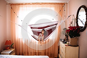 Full length portrait of pretty little girl with long hair in Christmas trouses and white T-shirt sitting comfortably in