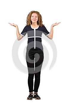 Full length portrait of pretty teenage girl, curly hair, spread her arms balancing hands gesture as looking to camera, giving two