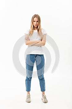 Full length portrait of a pretty young caucasian woman wearing jean and looking upset with her arms crossed