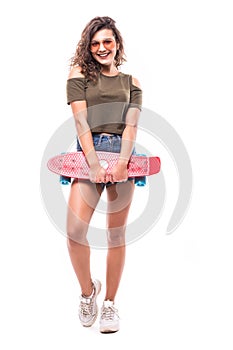 Full length portrait of a pretty young woman in sunglasses posing with skateboard while standing and looking at camera isolated