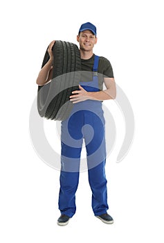 Full length portrait of professional auto mechanic with tire on background