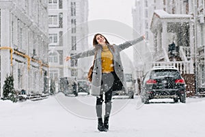 Full-length portrait of romantic european lady wears long coat in snowy day. Outdoor photo of inspired brunette woman