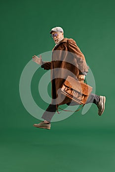 Full length portrait of running senior man with beard, detective wearing vintage hatand suit with big business bag