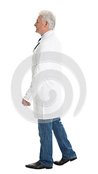 Full length portrait of senior doctor walking on white background