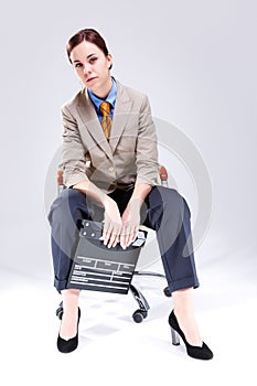 Full Length Portrait of Seriously Looking Caucasian Female Posing in Beige Blazer in Chair with Actioncut Indoors