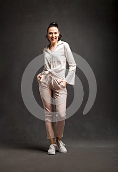 Full length portrait of smiley stylish woman over grey background