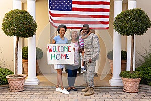 Full length portrait of smiling african american family of soldier celebrating return at entrance