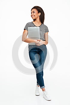 Full length portrait of a smiling african teenager holding laptop