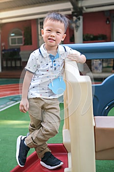 Full length portrait of smiling Asian 3 - 4  years old toddler boy pose for camera during having fun on climbing frame at