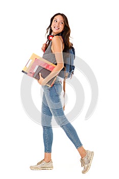 Full length smiling asian college student walking against isolated white background with books and bag