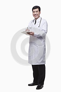 Full Length Portrait of Smiling Doctor Writing Medical Record and Looking At Camera