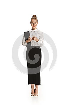 Full length portrait of a smiling female teacher holding a folder isolated against white background