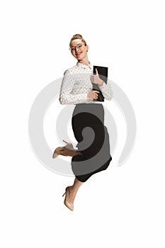 Full length portrait of a smiling female teacher holding a folder jumping against white background