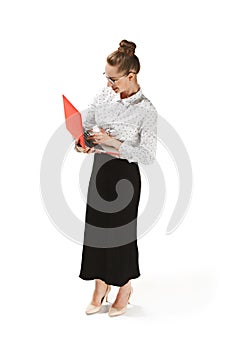 Full length portrait of a smiling female teacher holding a laptop isolated against white background