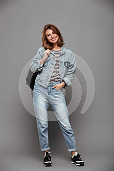 Full length portrait of a smiling girl in denim jacket
