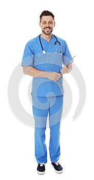 Full length portrait of smiling male doctor in scrubs with clipboard. Medical staff