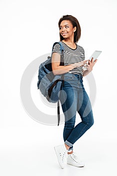 Full length portrait of a smiling teenage girl wearing backpack