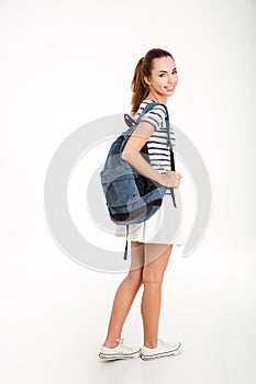 Full length portrait of a smiling woman with backpack standing