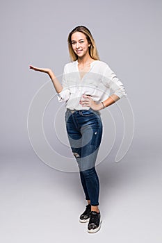 Full length portrait of a smiling woman holding copy space on her palm over gray background