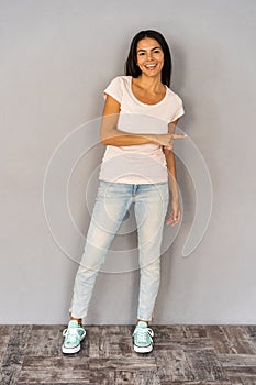 Full length portrait of a smiling woman holding copyspace on the palm isolated on a gray background.